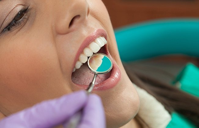 Dentist examining patient's smile after metal free dental restoration placement