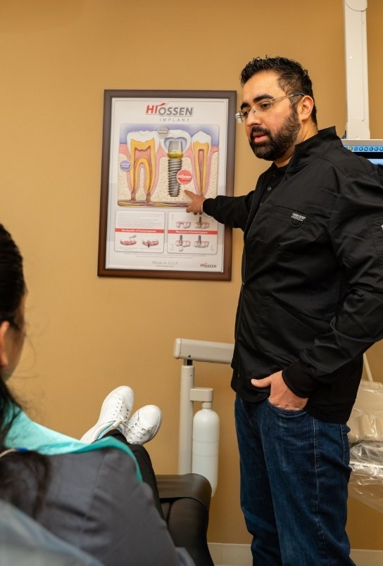 Dentist showing patient a dental implant poster