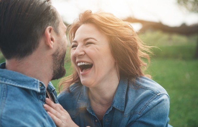 Man and woman laughing together after dental implant tooth replacement