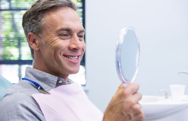 Man looking at smile after dental implant tooth replacement