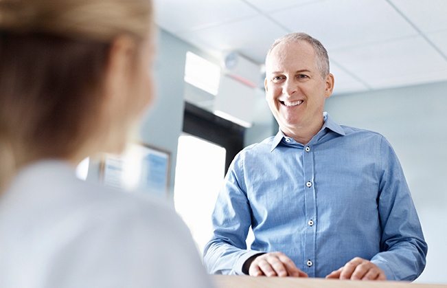 Smiling man checking in at dental office reception desk