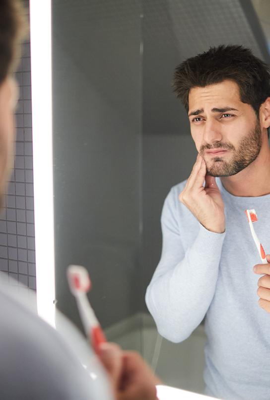 Man in need of emergency dentistry holding his cheek