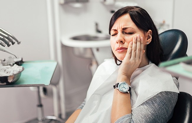 Woman at dental office for emergency dentistry holding cheek