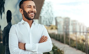 Man with dental implants in Auburn, WA smiling outside with arms folded