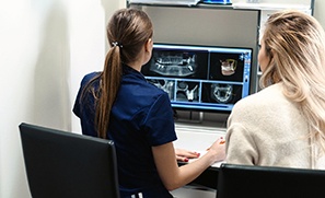Implant dentist in Auburn examining X-rays with dental assistant