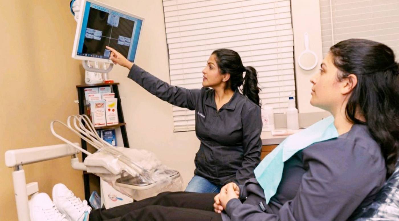 Dentist and patient looking at digital x-rays on computer screen