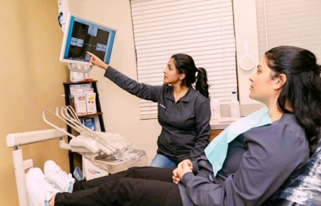 Doctor Dhaliwal and dental patient looking at x-rays on computer screen