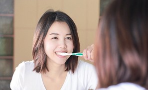 Woman brushing teeth to prevent dental emergencies in Auburn