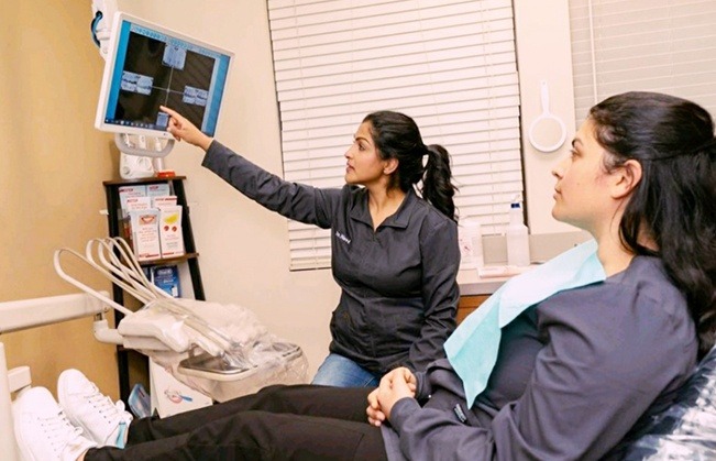 Dentist and patient looking at x-rays during dental checkup and teeth cleaning visit