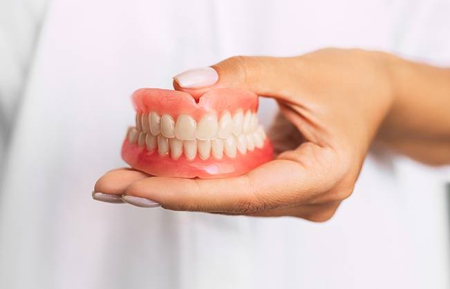 Person holding a full denture