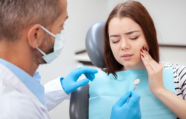 Woman in need of root canal holding cheek in pain