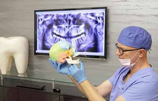 Dentist using model to explain TMJ treatment options